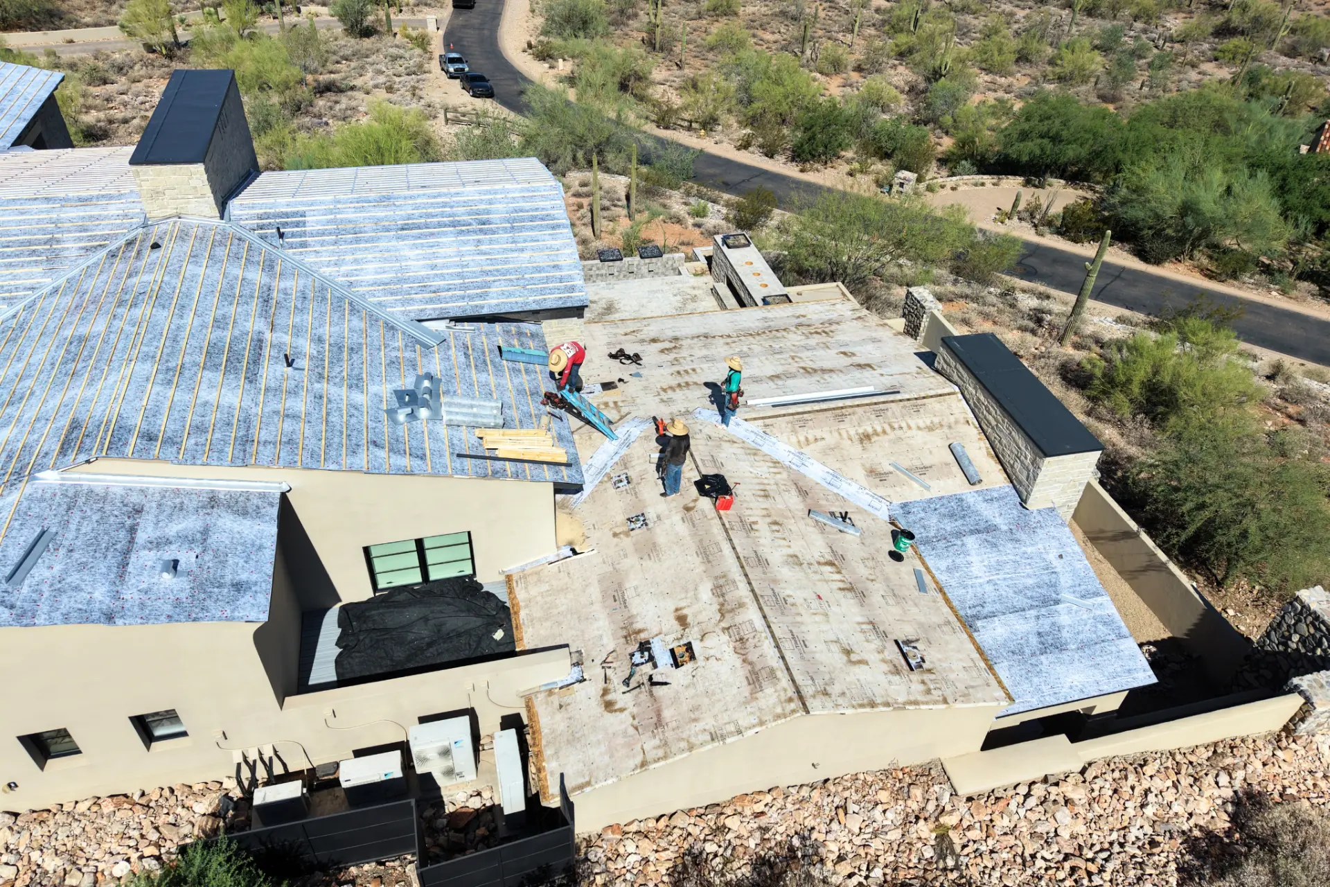 Roofing crew installing underlayment on a hillside Arizona home